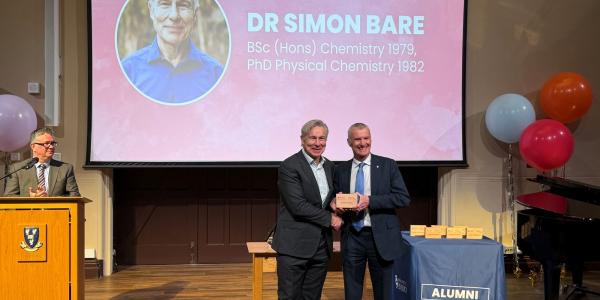 Simon receiving the alumni award