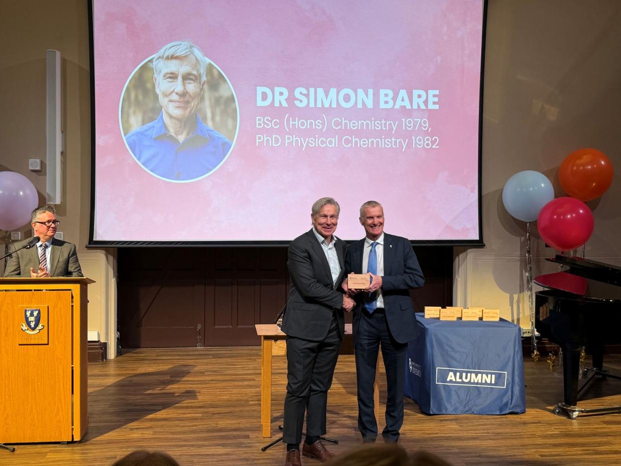 Simon receiving the alumni award
